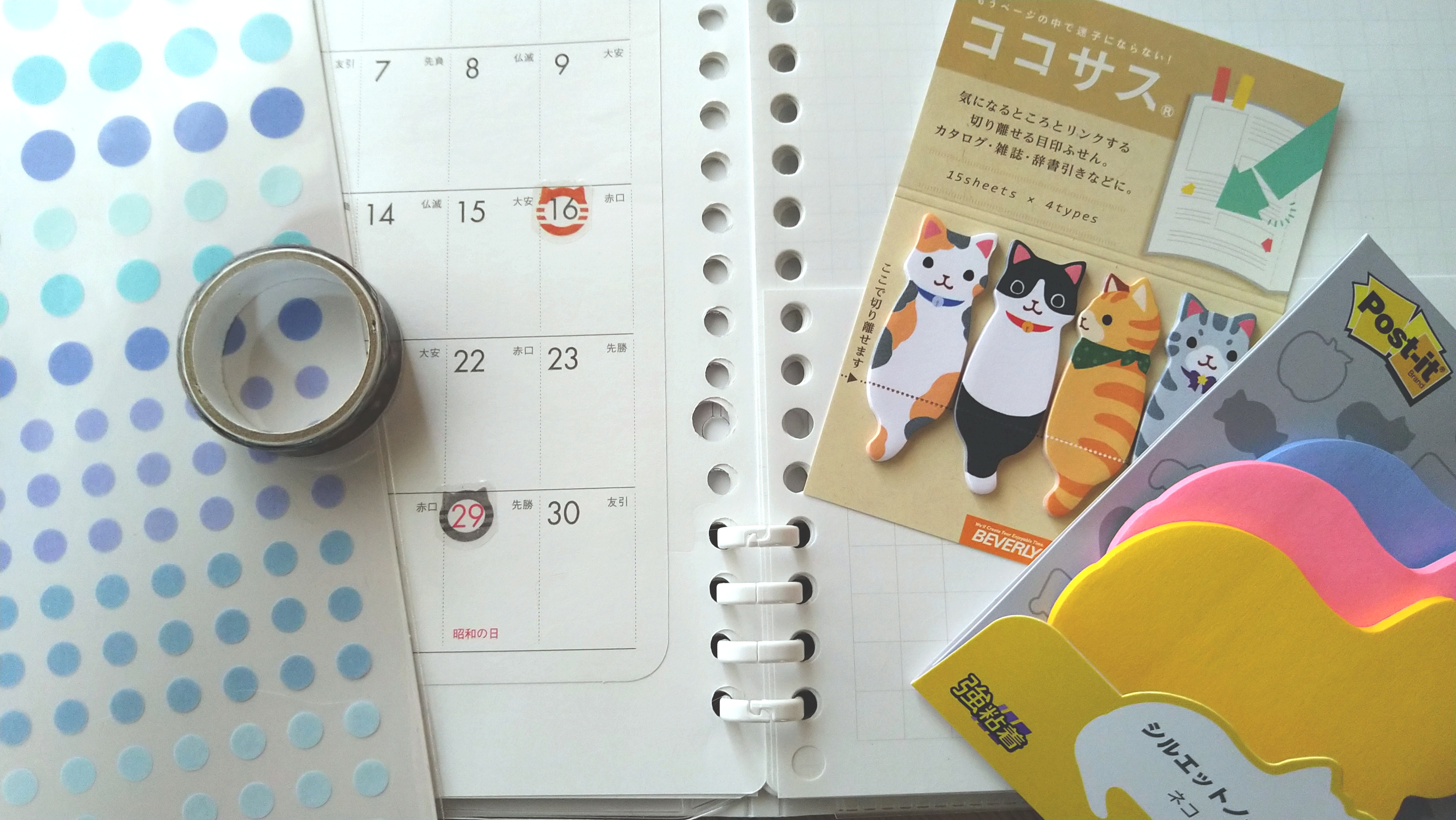 デスクに広げられた2022年4月のマンスリー手帳と、猫モチーフの付箋やシールなどのデコレーション用文房具一式
